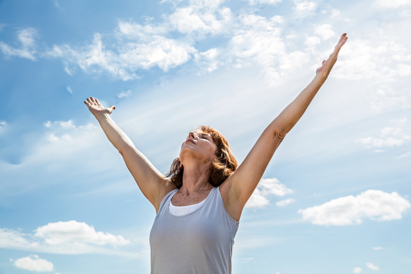 Zen middle aged yoga woman raising arms up to breathe
